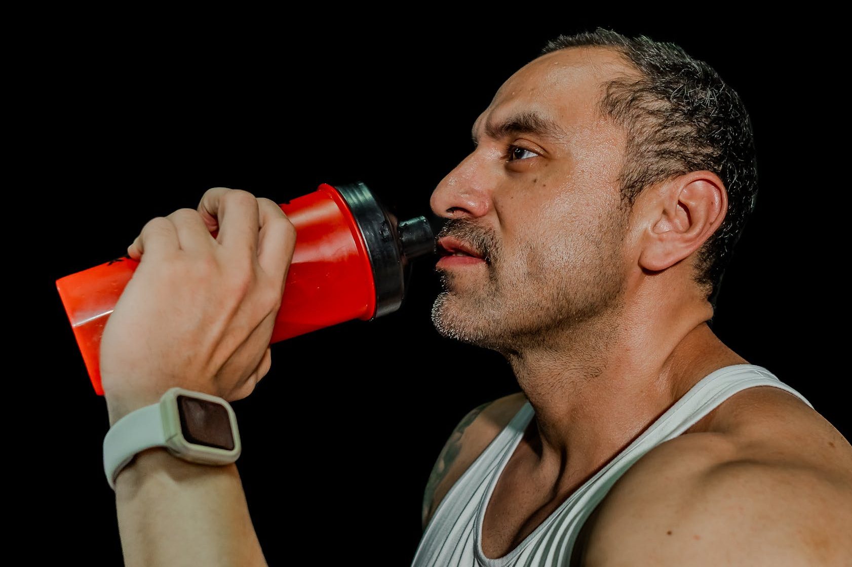 man drinking from a gym shaker bottle in studio
